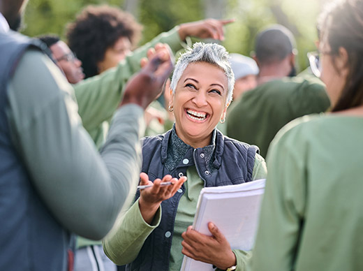 photograph of an older woman laughing as she talks with two people facing her