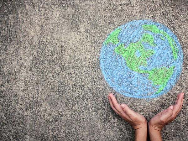 hands holding a chalk drawing of Earth