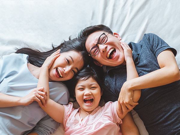 Happy Asian family laying on bed smile