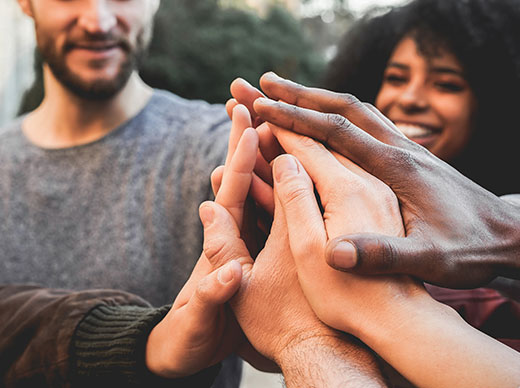 Young happy people stacking hands outdoor