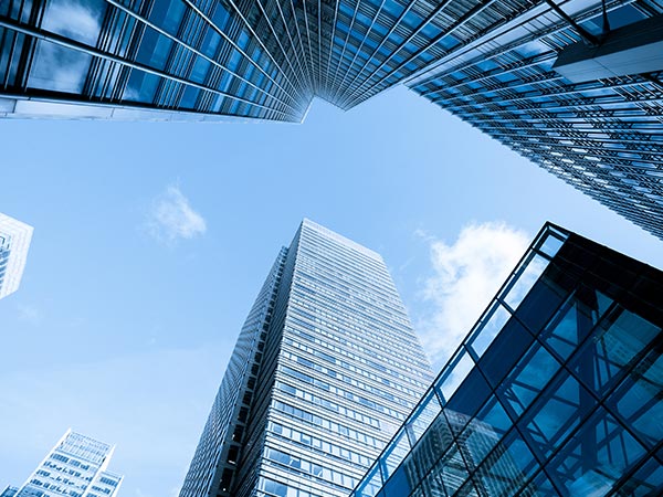 photo looking up at blue sky surrounded by skyscrapers