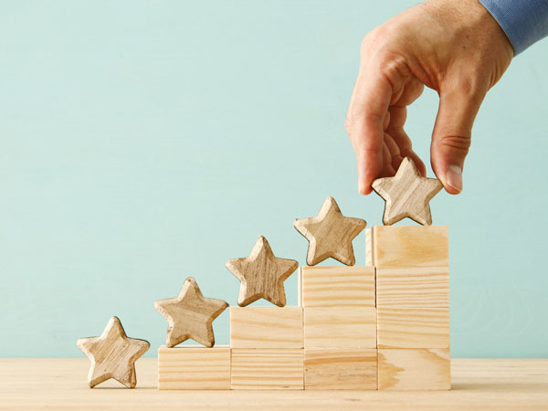 hand stacking wooden stars on top of ascending blocks
