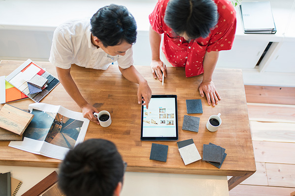 Overhead view of a team of architects or interior designers having a meeting and looking at a digital tablet