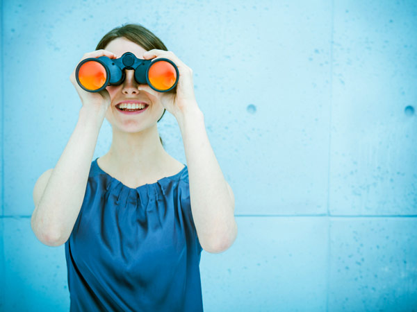 Businesswoman looking through binoculars