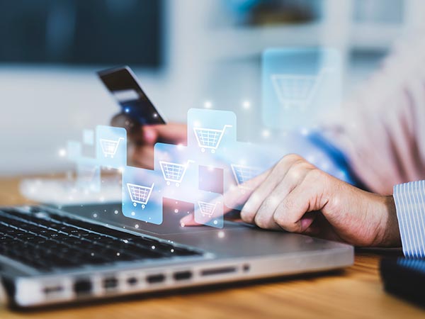 e-commerce image of woman typing on laptop with digital shopping carts in background