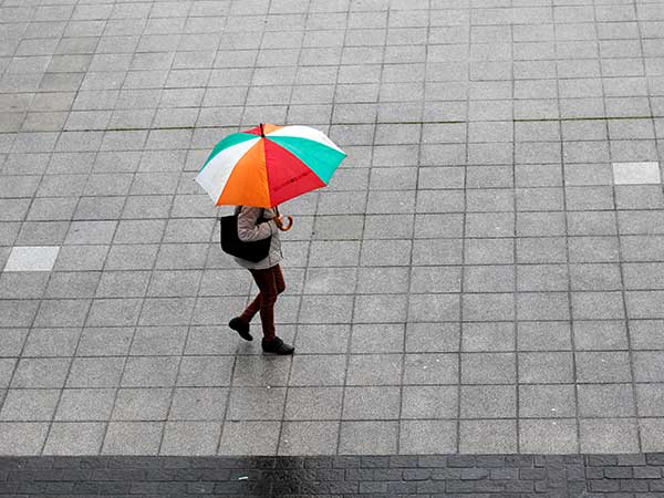 birds eye view of a person walking across a plaza under a colorful umbrella