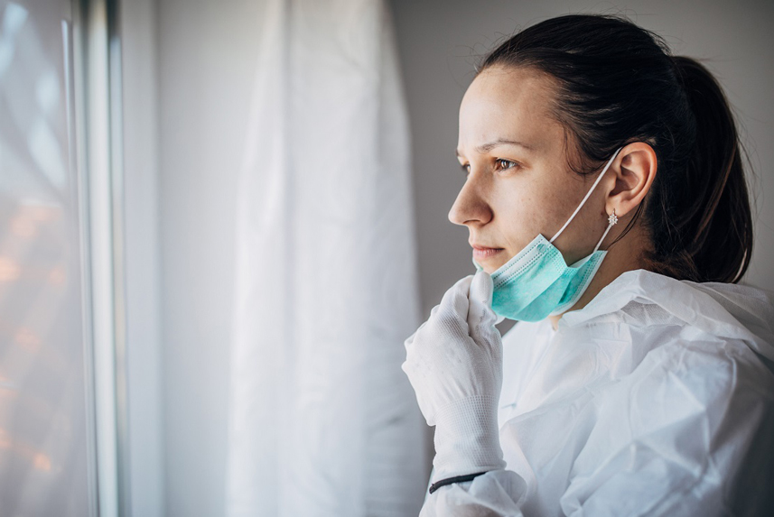 female doctor in protective suit, looking concerned through the hospital window.