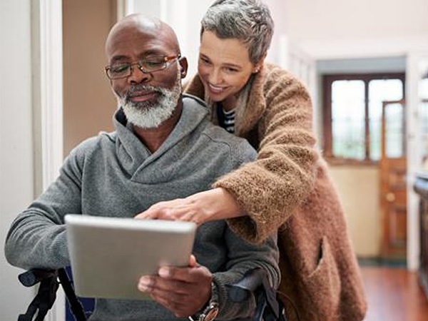man and woman looking at ipad in hallway, smiling