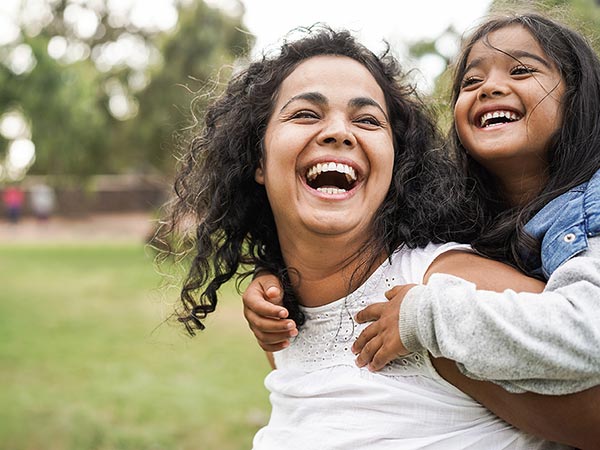 Smiling child riding on the shoulders of their laughing parent