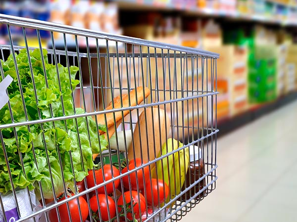 photo of a shopping cart in a grocery aisle filled with different types of produce