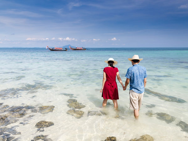 Couple holding hand walking into sea