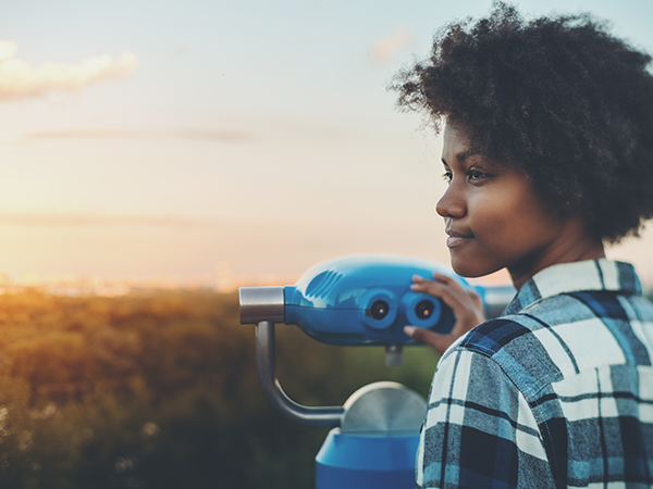 A young person preparing to look through public binoculars.