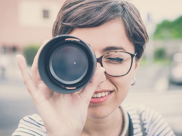 woman looking through a camera's zoom lens