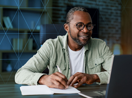 Smiling man using a laptop in an office setting.