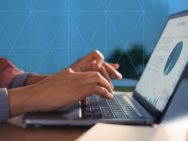 Person typing on a laptop displaying a data dashboard with charts.