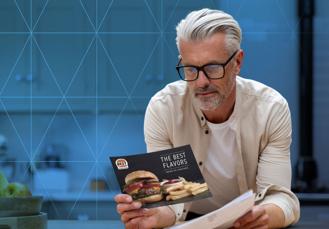 Man reviewing a restaurant promotional flyer featuring a burger and fries while holding mail
