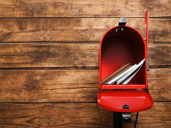 Photo of an open red mailbox against a wood plank background