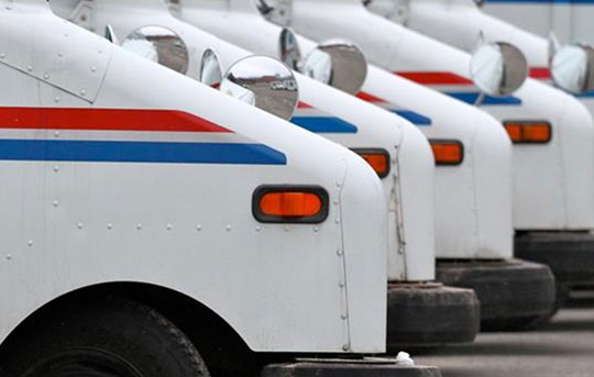 A line of parked USPS trucks
