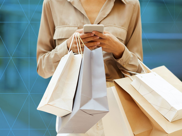 Person holding shopping bags while using a smartphone.
