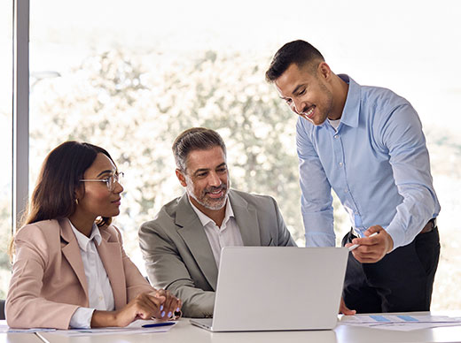 Photo of three business executives looking at a laptop