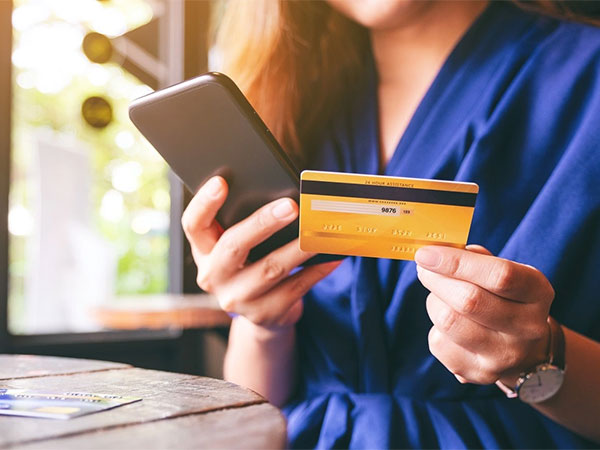 Closeup image of woman using credit card for purchasing and shopping online on mobile phone
