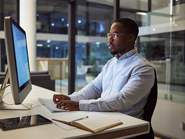 photo of an african american man working at a computer in a modern office setting