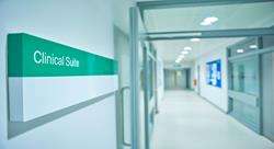 long and empty hospital corridor with a close up view of a door sign that says Clinical Suite
