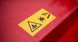 Yellow warning label on a red lawn mower