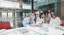 A group of people in a conference room looking at a laptop on a table