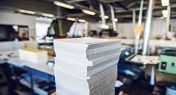 Picture of printing shop interior with a selective focus on pile of sheets.