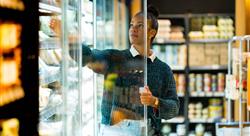 Woman choosing food from refrigerated display in supermarket
