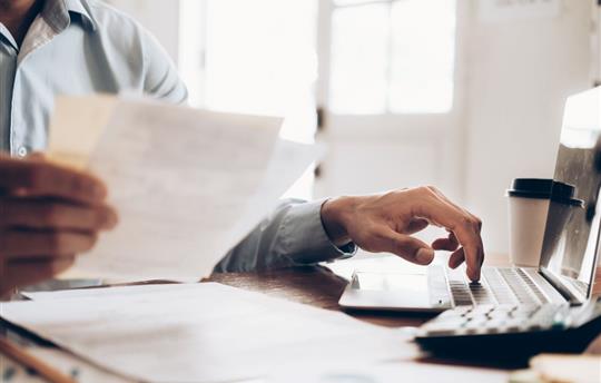 Male accountant or banker using calculator and looking at invoice
