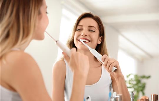 woman brushes teeth with eletric toothbrush
