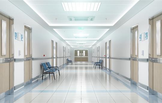 Long, bright and empty hospital corridor with doors and chairs