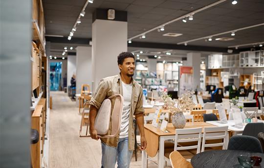 Man carrying folding chair to shop counter