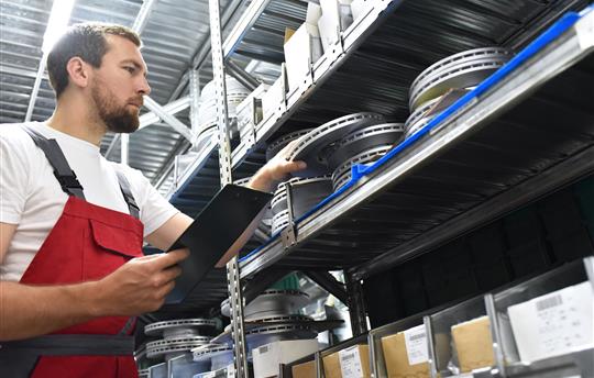 friendly worker in a warehouse and trade for car spare parts of a car repair shop