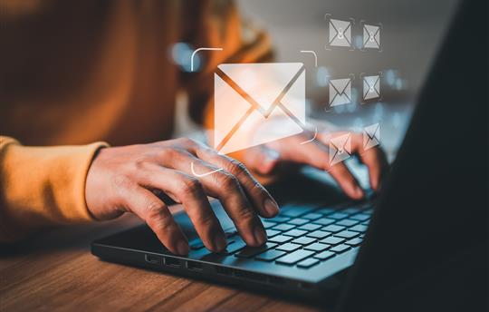 person types on laptop keyboard, answering email