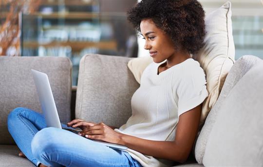 woman sitting comfortably on her couch and using her laptop