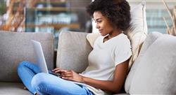 woman sitting comfortably on her couch and using her laptop