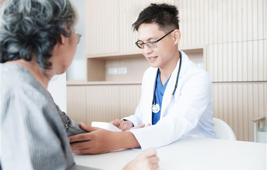 Close-up of physician checking senior woman’s blood pressure with sphygmomanometer