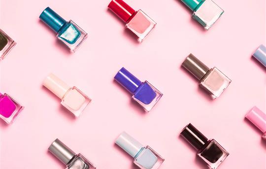 close-up of nail polish bottles patterned on a pink background
