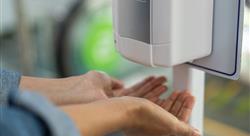 Close up of woman holding hands under automatic sanitizer dispense