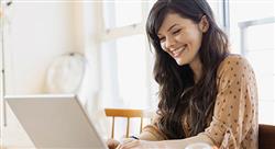 smiling woman with long brown hair using a laptop