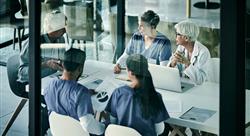 Healthcare team sitting at a table in blue scrubs having a meeting