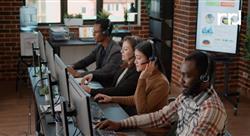 Four call center employees sitting at a table wearing headsets