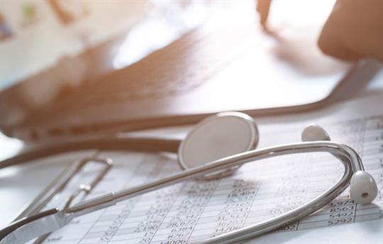 stethoscope on open binder in front of open laptop