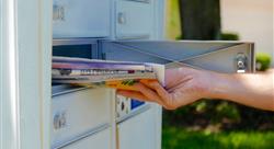 A hand is pulling a pile of mail out of a mailbox