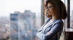 female businesswoman with arms crossed looking out office window