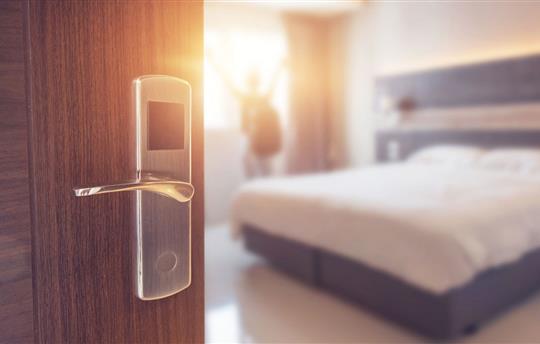 Opened door of hotel room in morning with background blurred happy backpacker traveler stay in hotel, sunlight effect.