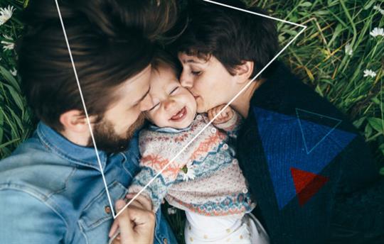 young parents kissing the cheeks of their laughing toddler